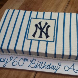 A rectangular cake with blue vertical stripes and a New York Yankees logo in the center sits proudly. Created by a renowned bakery, the cake rests on a white base with blue icing that reads "Happy 60th Birthday." The word following "Birthday" is partially cut off and unclear.